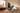 Man pulls an overhead bar on a digital home gym as its screen displays workout metrics.