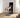 Woman kneels on a connected home gym and extends one leg against cable resistance.