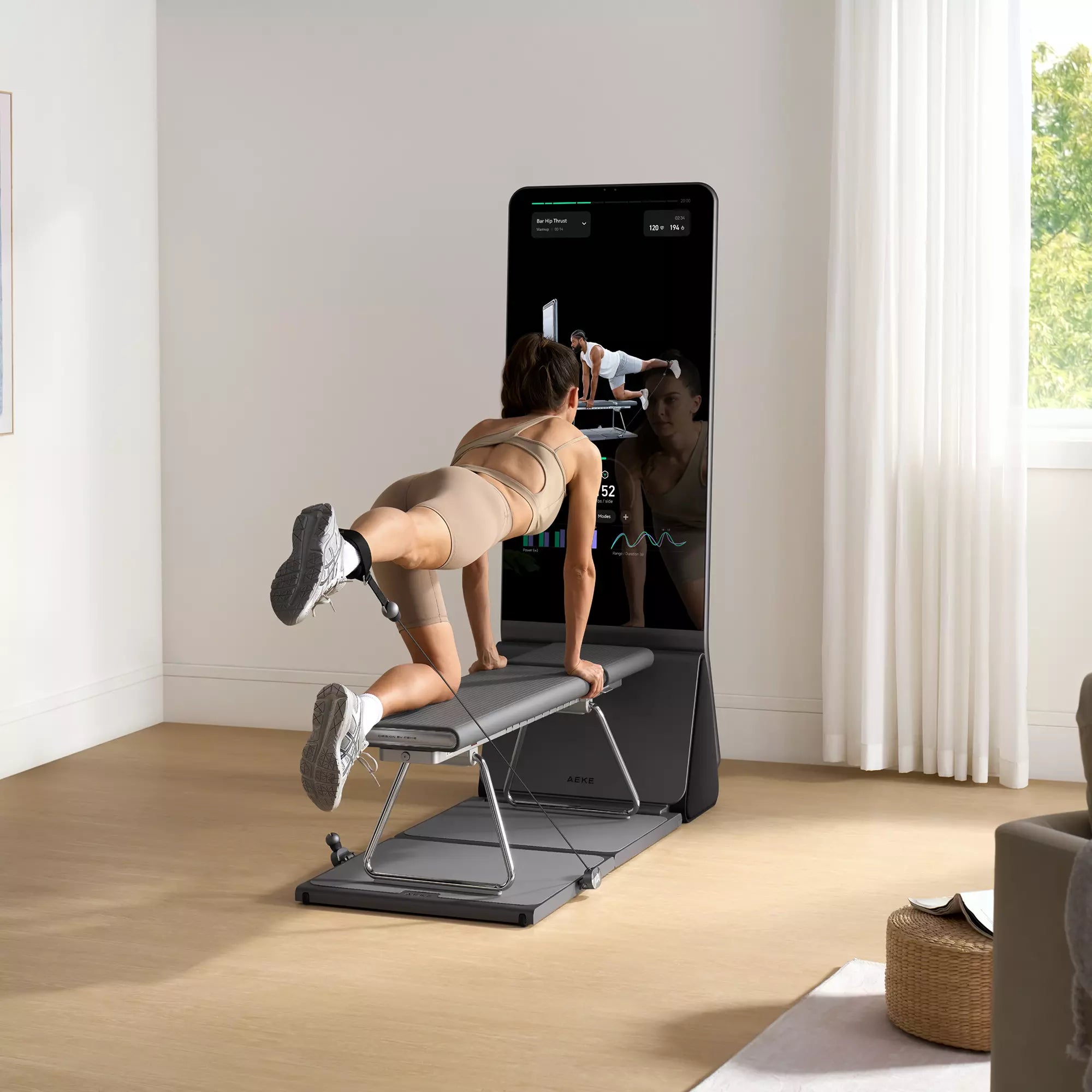 Woman kneels on a connected home gym and extends one leg against cable resistance.