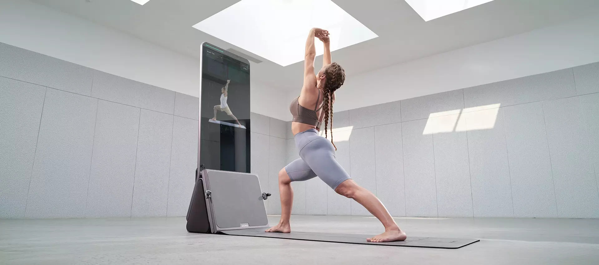 Woman stretching in a lunge beside a tall interactive fitness screen