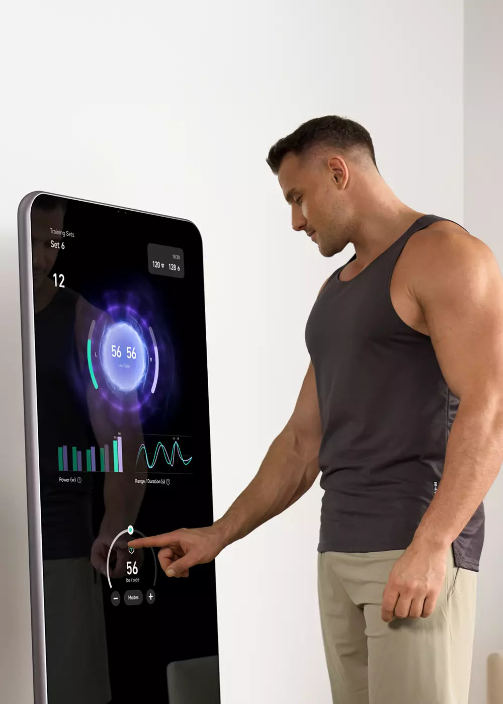 Man points to training-set metrics and charts on a digital strength machine touchscreen.