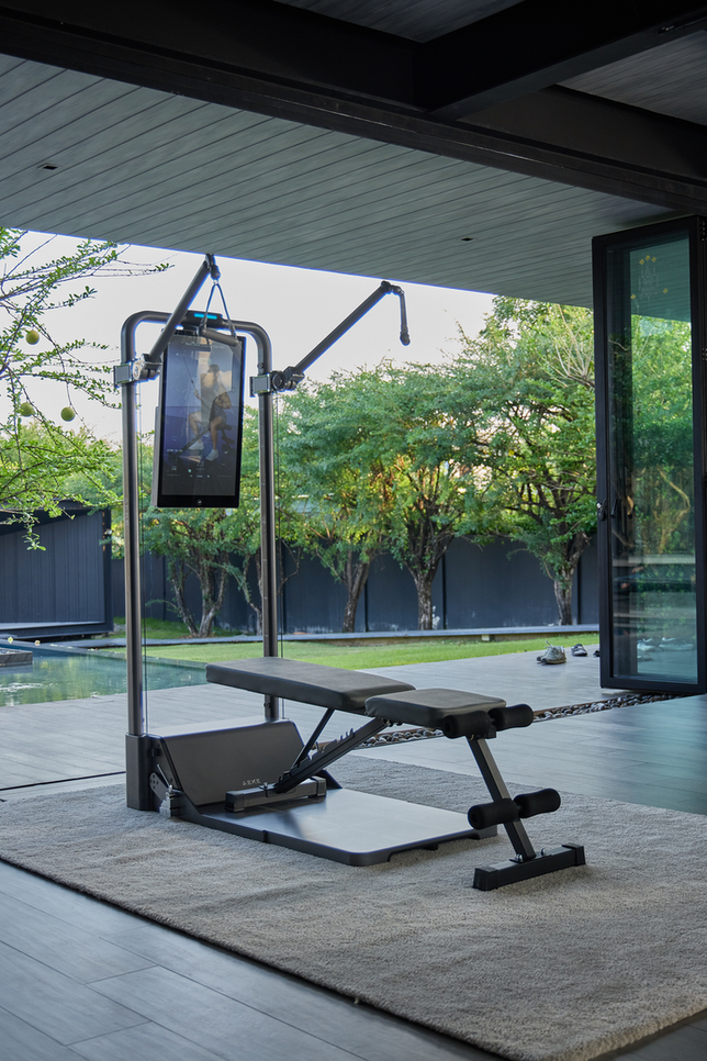 Digital strength-training machine with a touchscreen and bench set up in a bright home gym