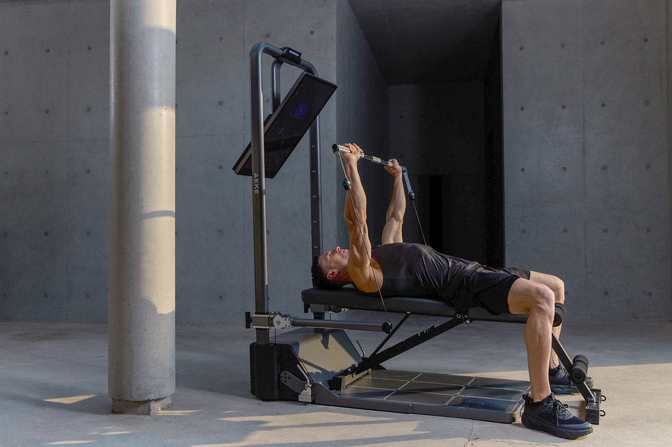 Man lying on a flat workout bench and pressing cable handles upward.