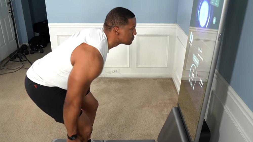Man performing a squat workout in front of the AEKE K1 smart home gym mirror