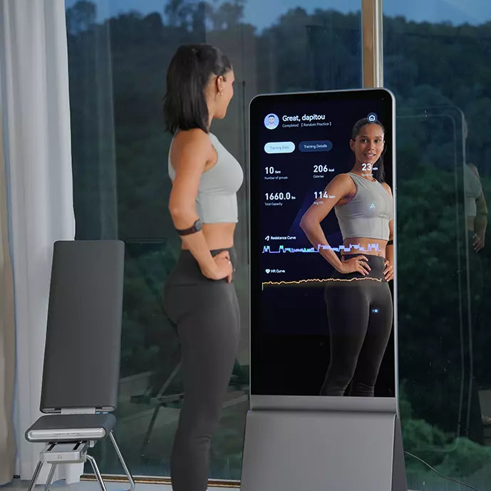 A woman stands before a smart fitness mirror that displays her reflection and real-time workout performance data.